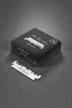 My-Blades Platinum 100 half razor blades in matte black box with loose branded blade placed in front on dark studio background.