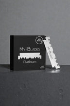 My-Blades Platinum 100 half blades in matte black packaging displayed on textured pedestal with single double-edge blade standing upright beside the box.
