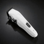 Angled studio image of the white Tensor1 clipper on a dark textured surface, showcasing its clean modern design, ergonomic controls, and precision blade head.